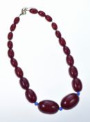 A graduated single strand of cherry amber necklace made up of twenty one oval beads, the largest