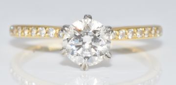 An 18ct gold ring set with a round brilliant cut diamond of approximately 0.8ct and with further
