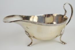 George V hallmarked silver sauce boat with gadrooned edge, loop handle and raised on three feet,