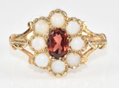 A 9ct gold ring set with an oval cut garnet surrounded by opals, 2.5g, size N