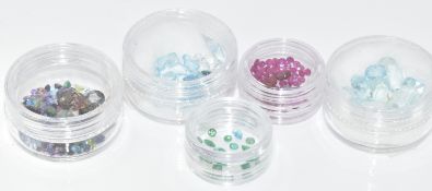 A collection of loose gemstones including emeralds, rubies, topaz, aquamarines, etc