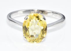 A 9ct white gold ring set with an oval cut synthetic yellow sapphire, in Art Deco box, 1.8g, size J