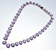 A 14k gold necklace set with graduated oval cut amethysts, the largest 13.6 x 10.8 x 6.6mm and