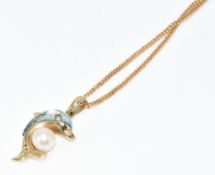 A 9ct gold pendant in the form of a dolphin set with topaz, a pearl and diamond eye, on 9ct gold