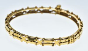 A yellow metal bangle with bar and cross decoration, tests as 21k gold, 20.4g