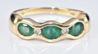 An 18ct gold ring set with three oval cut emeralds and two diamonds, 3.1g, size P
