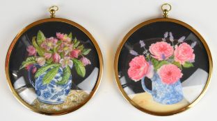 Pair of circular watercolours of Hellebores and roses with suspension loops, signed with monogram
