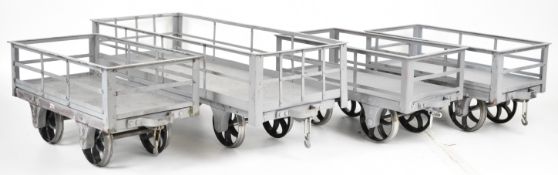 Four grey 5 inch gauge Ffestiniog slate wagons with curved spoked wheels, three having riveted