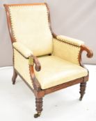 Regency or Victorian mahogany upholstered armchair raised on brass castors, and with brass reading