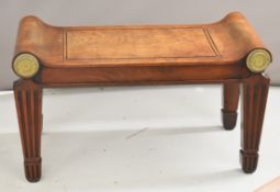 Regency mahogany window seat of scrolling form, with circular ormolu mounts to both sides, raised on