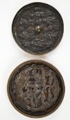 Two bronze or similar Chinese circular mirrors with relief moulded decoration, largest diameter 12.