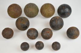 Thirteen various cast iron cannon balls, each between 5-10cm in diameter.