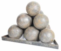 Ten cast iron cannon balls each approximately, 10cm in diameter, on an iron monkey, each ball