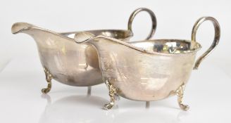 Pair of modern hallmarked silver sauce boats, each with scroll handles and raised on three feet,
