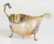 George V hallmarked silver sauce boat with scroll handle and raised on three hoof feet, Birmingham