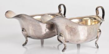Pair of modern hallmarked silver sauce boats, each with wavy edges and raised on three feet,