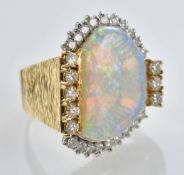 An 18ct gold ring set with a white opal of approximately 6ct surrounded by round cut diamonds, the
