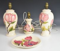 Three Moorcroft table lamps and a charger decorated in the Magnolia pattern, tallest 34cm.