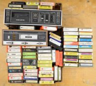 Approximately seventy 8-Track Cassettes and two vintage 8-Track players. Cassettes are mainly Hard