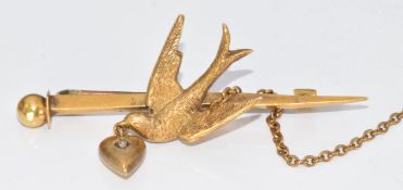 A 15ct gold brooch c1910 in the form of a swallow, the beak holding a drop heart set with a rose cut