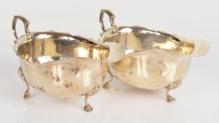 Pair of George V hallmarked silver sauce boats with shaped edges and scroll handles, raised on three
