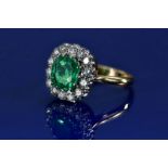 An 18ct gold ring set with cushion cut emerald of approximately 2ct surrounded by fourteen round