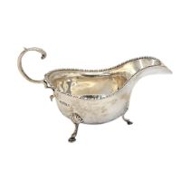 AN EARLY 20TH CENTURY SILVER SAUCE BOAT Having a beaded edge and tripod legs, hallmarked Charles
