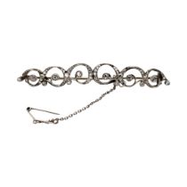 AN ART DECO WHITE METAL AND DIAMOND BROOCH Scrolled form set with mine cut stones, having a gun