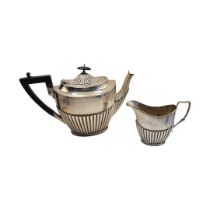 AN EARLY 20TH CENTURY SILVER TEAPOT AND CREAM JUG Having half flute decoration to base, hallmarked