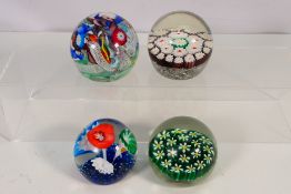 Four glass paperweights to include two Murano examples.