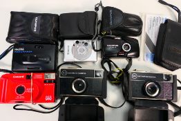 A collection of vintage cameras to include an Olympus Mju II, Halina, Canon and other.