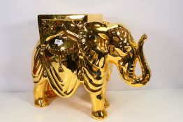 A gilt ceramic plant stand in the form of a caparisoned elephant, approximately 45 cm (h).