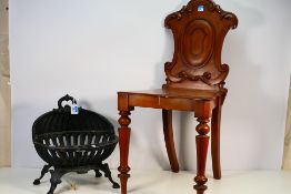 A wooden chair with carved decoration to the back rest and a small cast iron log basket. [2].
