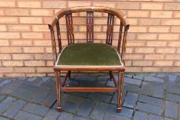An Edwardian mahogany open armchair with inlaid decoration and upholstered seat.