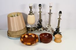 Four table lamps with shades and two wooden bowls.