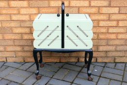 A Harrods cantilever sewing box, approximately 78 cm x 59 cm x 30 cm, on castors.