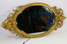 A gilt framed wall mirror, the decorative moulded frame with floral surmount,