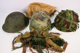 Three military helmets comprising a British Mk4 with liner and chin strap,