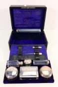 A leather clad travelling vanity case containing six jars and pots with silver plated covers and an