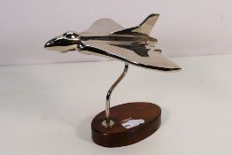 A chrome plated desk ornament of a jet plane, mounted wo wooden plinth, approximately 19 cm (h).
