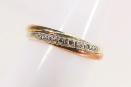 A 9ct gold tri-tone ring set with seven small diamonds, size S, approximately 3.6 grams.