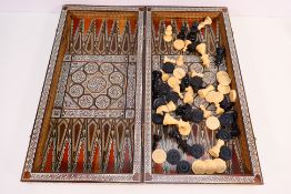 A chessboard box with inlaid decoration containing chess and draughts pieces, 7 cm (h) king.