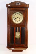 An oak cased wall clock, Arabic numerals to the dial, with key and pendulum, 78 cm (l).