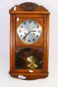 A vintage HAC wall clock with carved decoration, Arabic numerals to the dial, with key and pendulum,