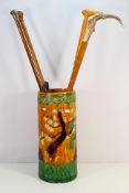 A Chinese ceramic umbrella stand containing a quantity of walking sticks including one with silver