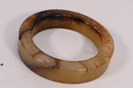 A Chinese jade or similar hardstone disc or bangle with brown inclusions, 8.2 cm (d).