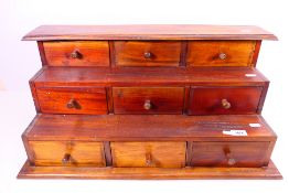 A vintage desktop bank of nine drawers, approximately 30 cm x 64 cm x 30 cm.