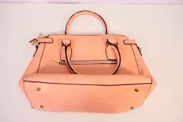 A handbag in salmon with gold coloured detail,