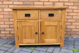 An Oak Furniture Land sideboard with two short drawers over enclosed cupboards,