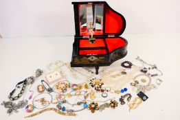 A musical jewellery box containing a quantity of costume jewellery to include rings, earrings,